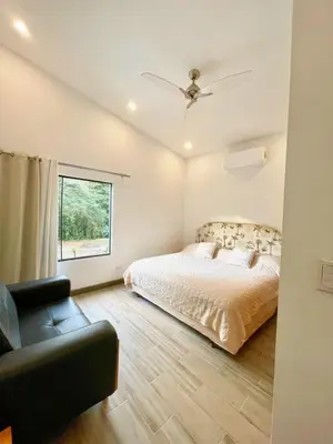 a bedroom with a bed and a chair and a window at Jaco Roca Bruja in Jacó