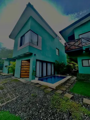 a house with a swimming pool in front of it at Jaco Roca Bruja in Jacó