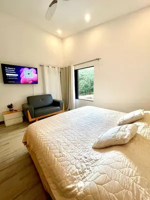 a bedroom with a large bed and a chair at Jaco Roca Bruja in Jacó