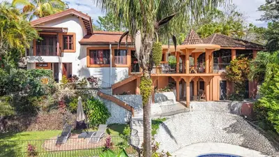 a house with a palm tree in front of it at Casa Nubes - Ocean View in Carrillo