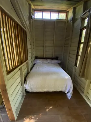 a bed in a wooden room with a window at Pipe's Cabin in San Pablo