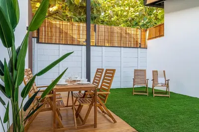 a patio with a wooden table and chairs on grass at Pinilla Living Studio 2 in Santa Cruz