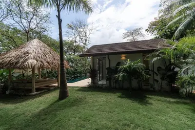 a small hut with a grass roof in a yard at GoldCoast Villa Santa Teresa in Santa Teresa Beach