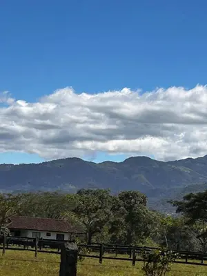 a house in a field with mountains in the background at Secure Retreat Near SJO and 27, Ideal for Families in Nuestro Amo