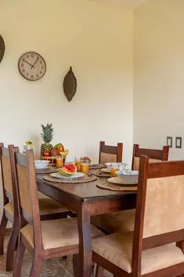 a dining room table with chairs and a clock on the wall at Villa Familiar 3BR Vistas al Valle & Naturaleza in Turrialba