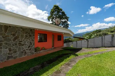 a house with an orange wall and a fence at Villa Familiar 3BR Vistas al Valle & Naturaleza in Turrialba