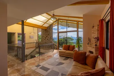a living room with a couch and a large window at Villa Familiar 3BR Vistas al Valle & Naturaleza in Turrialba