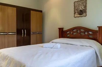 a bedroom with a white bed and wooden cabinets at Villa Familiar 3BR Vistas al Valle & Naturaleza in Turrialba