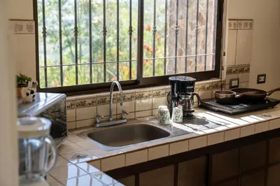 a kitchen counter with a sink and two windows at Villa Familiar 3BR Vistas al Valle & Naturaleza in Turrialba