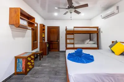 a bedroom with two bunk beds and a ceiling fan at Hospedaje Casa Blanca Tortuguero Carey in Tortuguero