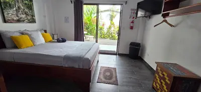 a bedroom with a bed with yellow pillows at Hospedaje Casa Blanca Tortuguero Carey in Tortuguero