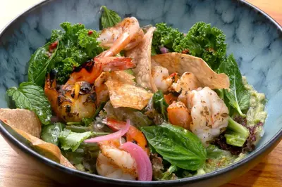 a bowl of food with shrimp and greens on a table at Olas Verdes Hotel in Nosara