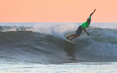 a man riding a wave on a surfboard in the ocean at Olas Verdes Hotel in Nosara