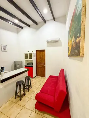 a living room with a red couch and a kitchen at Selva Partners Tamarindo in Matapalo