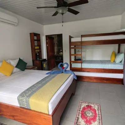 a bedroom with a bed and two bunk beds at Hospedaje Casa Blanca Tortuguero in Tortuguero