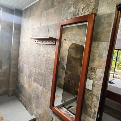 a mirror in a bathroom with a stone wall at Hospedaje Casa Blanca Tortuguero in Tortuguero