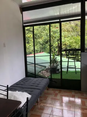 a room with a couch and a view of a tennis court at Casa Jenny in Quepos
