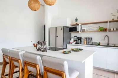a kitchen with a white counter and some chairs at Triskele Retreat - Combo Ocean and Earth in Esterillos