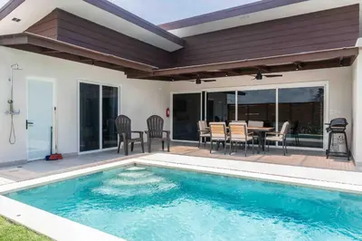 a swimming pool with a table and chairs next to a house at Triskele Retreat - Combo Ocean and Earth in Esterillos