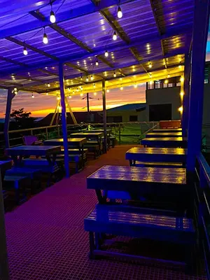a lit up patio with picnic tables and lights at Pupa House Hotel in Tamarindo