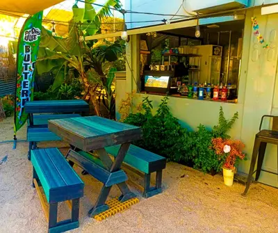 a picnic table and benches in front of a restaurant at Pupa House Hotel in Tamarindo