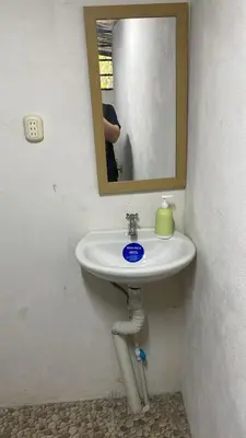 a bathroom sink with a mirror and a person taking a picture at Hostel La Bambú in Quepos
