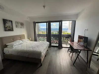 a bedroom with a bed and a table and windows at Sky Escalante Apartment in San José