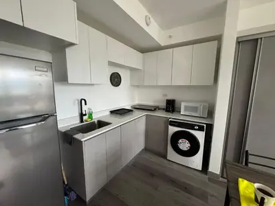 a kitchen with white cabinets and a sink and a dishwasher at Sky Escalante Apartment in San José