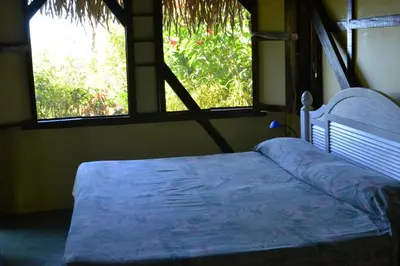 a bed in a room with two windows at TreeTops Inn in San Juanillo