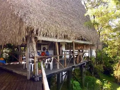 a hut with a straw roof and chairs on a deck at TreeTops Inn in San Juanillo
