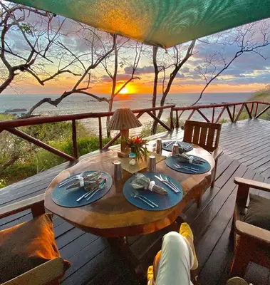 a table on a deck with a view of the ocean at TreeTops Inn in San Juanillo