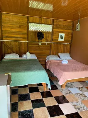 two beds in a room with a checkered floor at Tío Felix Eco Lodge in Fortuna