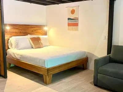 a small bedroom with a bed and a chair at Makanas Beach Bungalows in Santa Teresa Beach