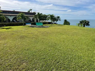 a large grassy field next to a building and the ocean at Caribbean View in Puerto Limón