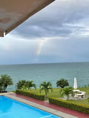 a rainbow over the ocean with a swimming pool at Caribbean View in Puerto Limón
