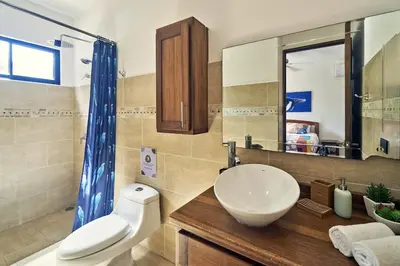 a bathroom with a sink and a toilet and a mirror at Villa Louise 4BR Modern Villa - Few Steps from the Beach in Santa Teresa Beach
