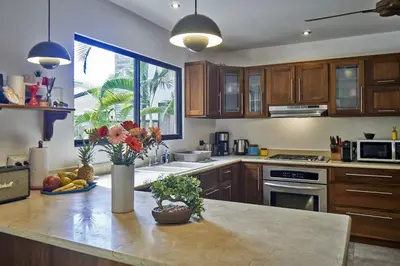 a kitchen with wooden cabinets and a vase of flowers on a counter at Villa Louise 4BR Modern Villa - Few Steps from the Beach in Santa Teresa Beach