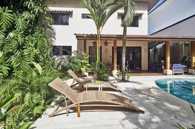 a villa with a swimming pool and palm trees at Villa Louise 4BR Modern Villa - Few Steps from the Beach in Santa Teresa Beach