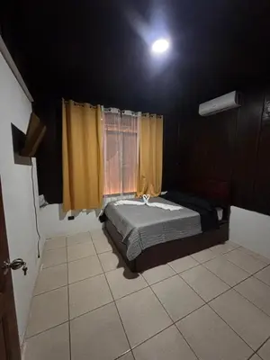 a bedroom with a bed and a window with yellow curtains at Cabana los Tutos, relajate y disfruta in Fortuna