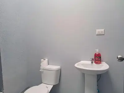 a white bathroom with a toilet and a sink at Airport Nest Costa Rica Hotel in Alajuela City