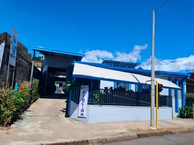 a white building with a sign in front of it at Airport Nest Costa Rica Hotel in Alajuela City