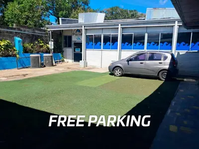 a car parked in front of a building with the words free parking at Airport Nest Costa Rica Hotel in Alajuela City
