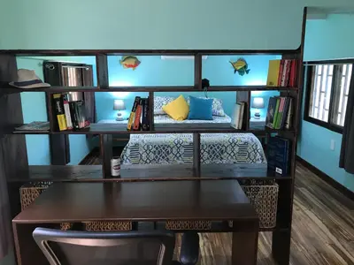 a room with a bed and a desk with books at Coco Loco Azul Boutique Apartments by Lucky Vacation Homes in Playa Junquillal