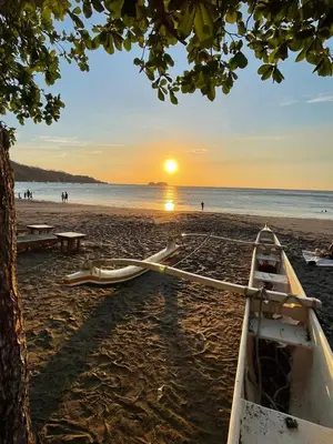 a boat sitting on a beach with the sunset at New house in Playa Hermosa in Playa Hermosa