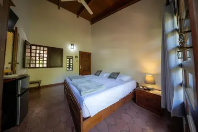 a bedroom with a large white bed and a kitchen at Villa Del Sol Boutique Hotel in Coco