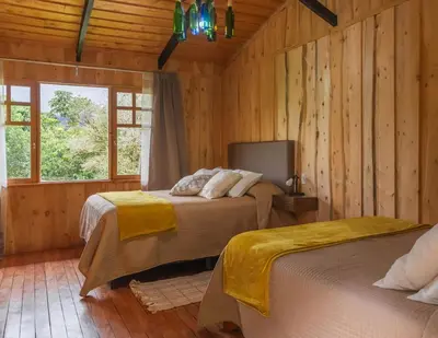 a bedroom with two beds in a room with wooden walls at Cedrela Eco-Lodge & Restaurante in El Copey