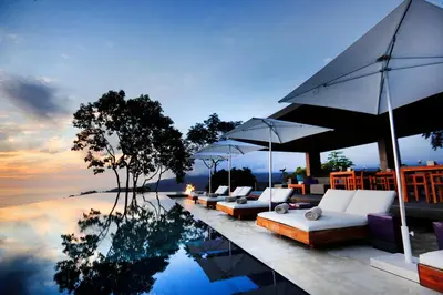a resort with a pool with couches and umbrellas at Kura Boutique Hotel Member of the Cayuga Collection in Uvita