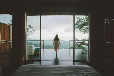 a woman walking out of a bedroom looking out the window at Kura Boutique Hotel Member of the Cayuga Collection in Uvita