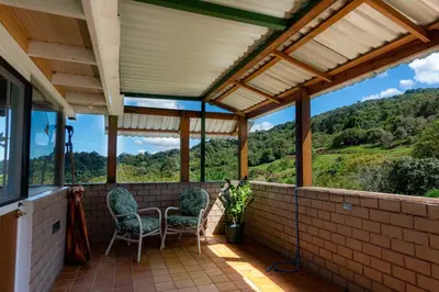 a screened porch with chairs and a view of the mountains at Bhoga Forest