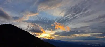 a cloudy sky with the sun setting behind a mountain at Infinite Stillness Farm in Buenos Aires